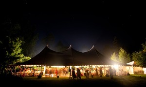 An open tent's dance floor is warmly lit by simple lighting.