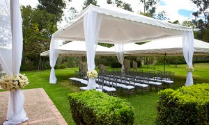 A tall open tent provides shades for outdoor seating for this wedding.