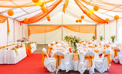 A banquet room is decorated in white and shades of orange and yellow.