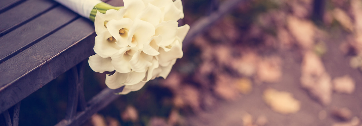 A white wedding bouquet on a bench.