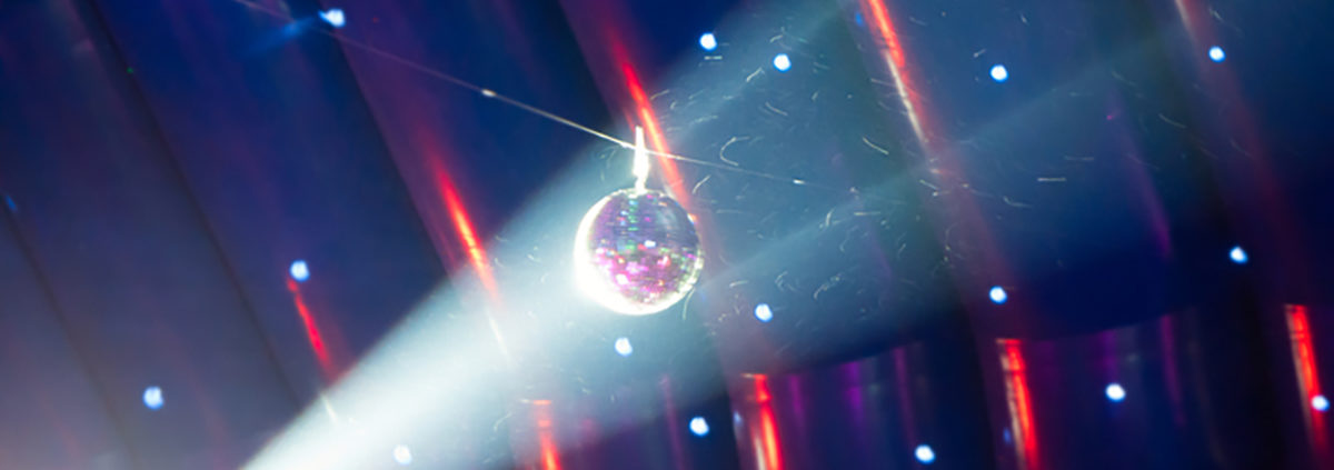 A light shines on a disco ball, with even more party lights present in the background.