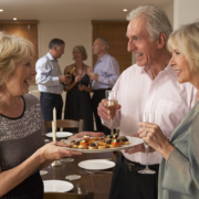 A woman is greeting a couple at a dinner party.