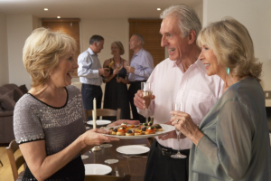 A woman is greeting a couple at a dinner party.