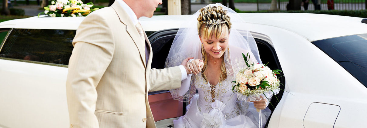 Happy bride and groom exiting limousine.