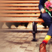 Bride and groom with bouquet outdoors on bench.