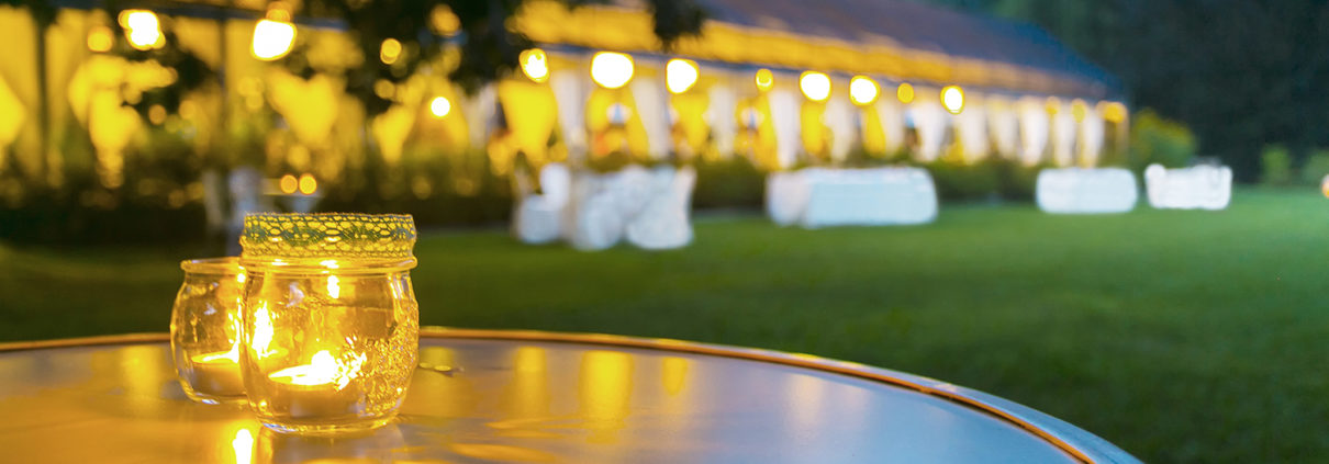 A large and beautifully lit outdoor tent for a wedding is pictured.